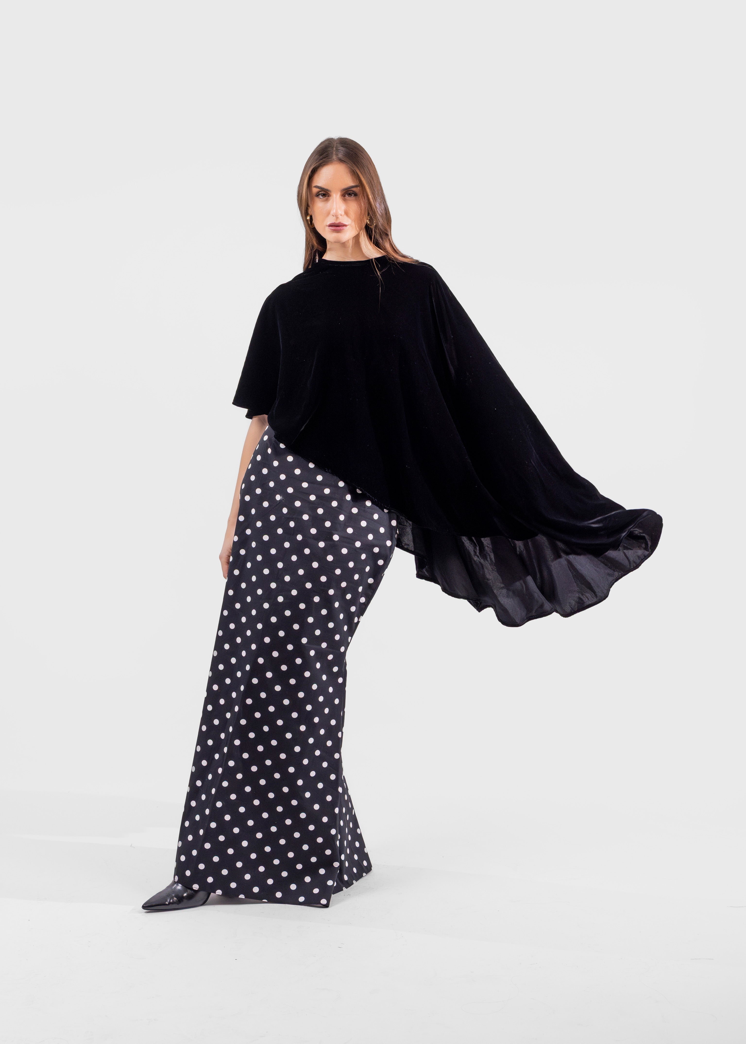 Woman wearing a black top and polka dot pants on a white background